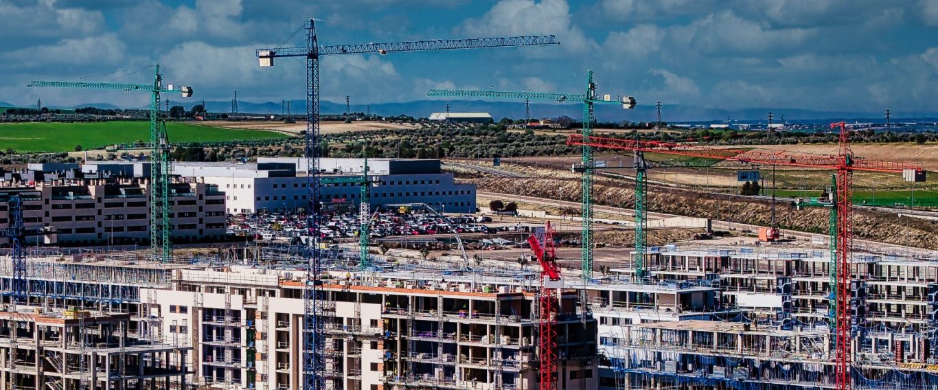 Obra en construcción con grúas y edificios en diversas fases de desarrollo.