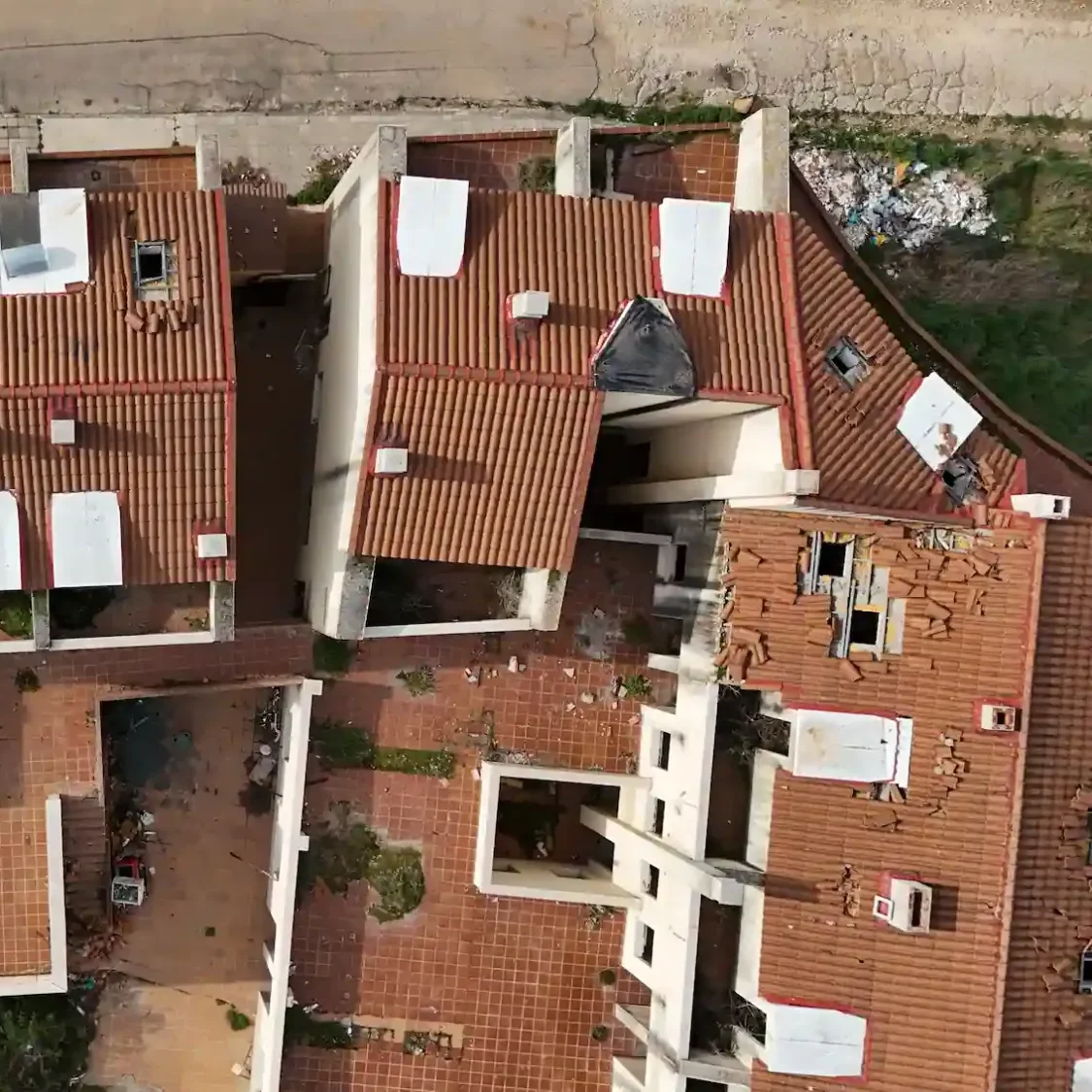 Dron inspeccionando tejado de edificio residencial con imágenes aéreas de alta precisión.