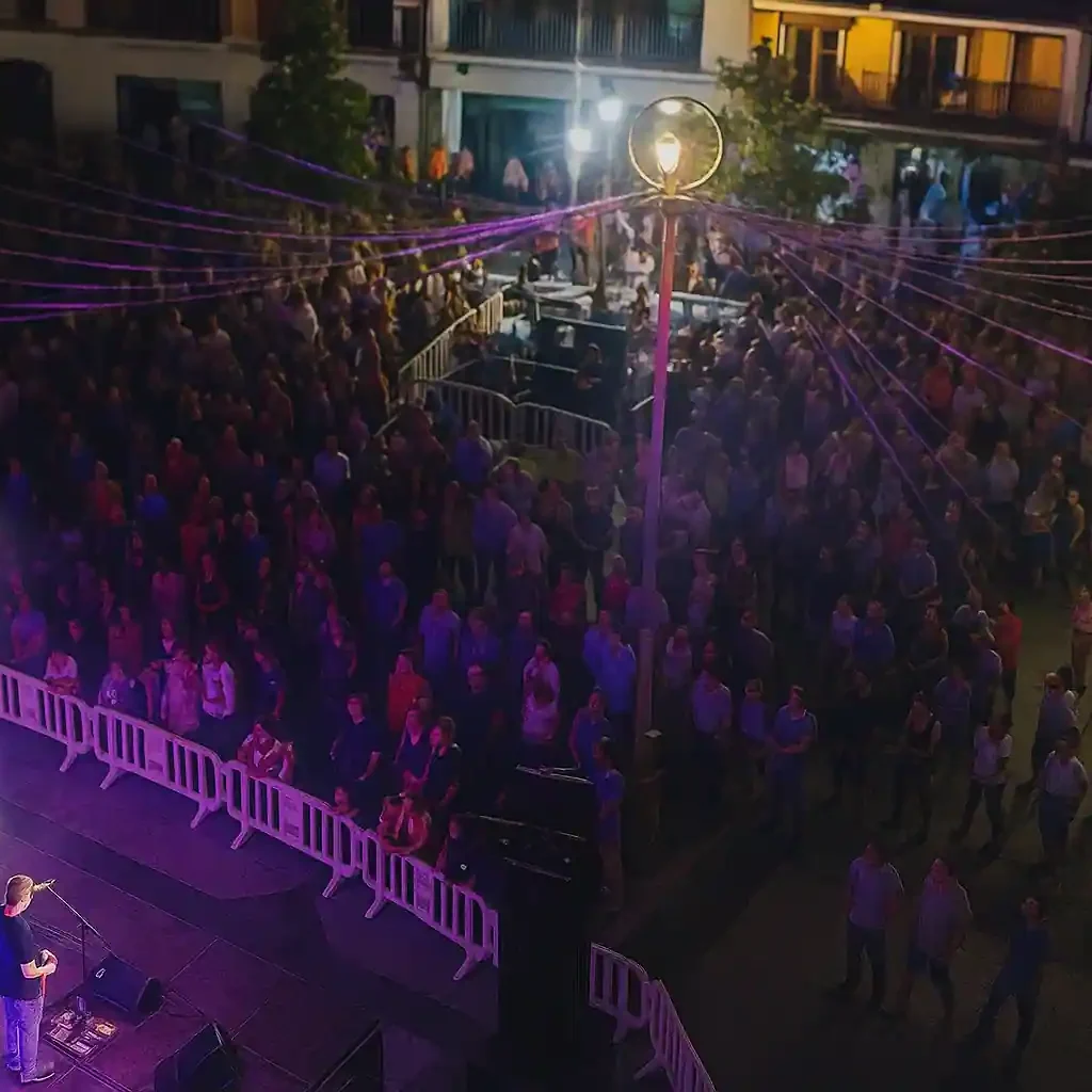 Vista aérea nocturna de un evento multitudinario con presencia de drones para vigilancia y control de aforo en espacio urbano